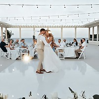 Emily and Stephen share their first dance at their destination wedding, twirling beneath the open sky as guests look on from beautifully decorated tables.