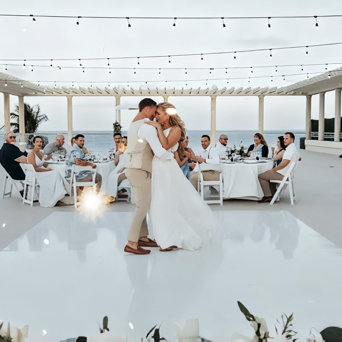 Emily and Stephen share their first dance at their destination wedding, twirling beneath the open sky as guests look on from beautifully decorated tables.