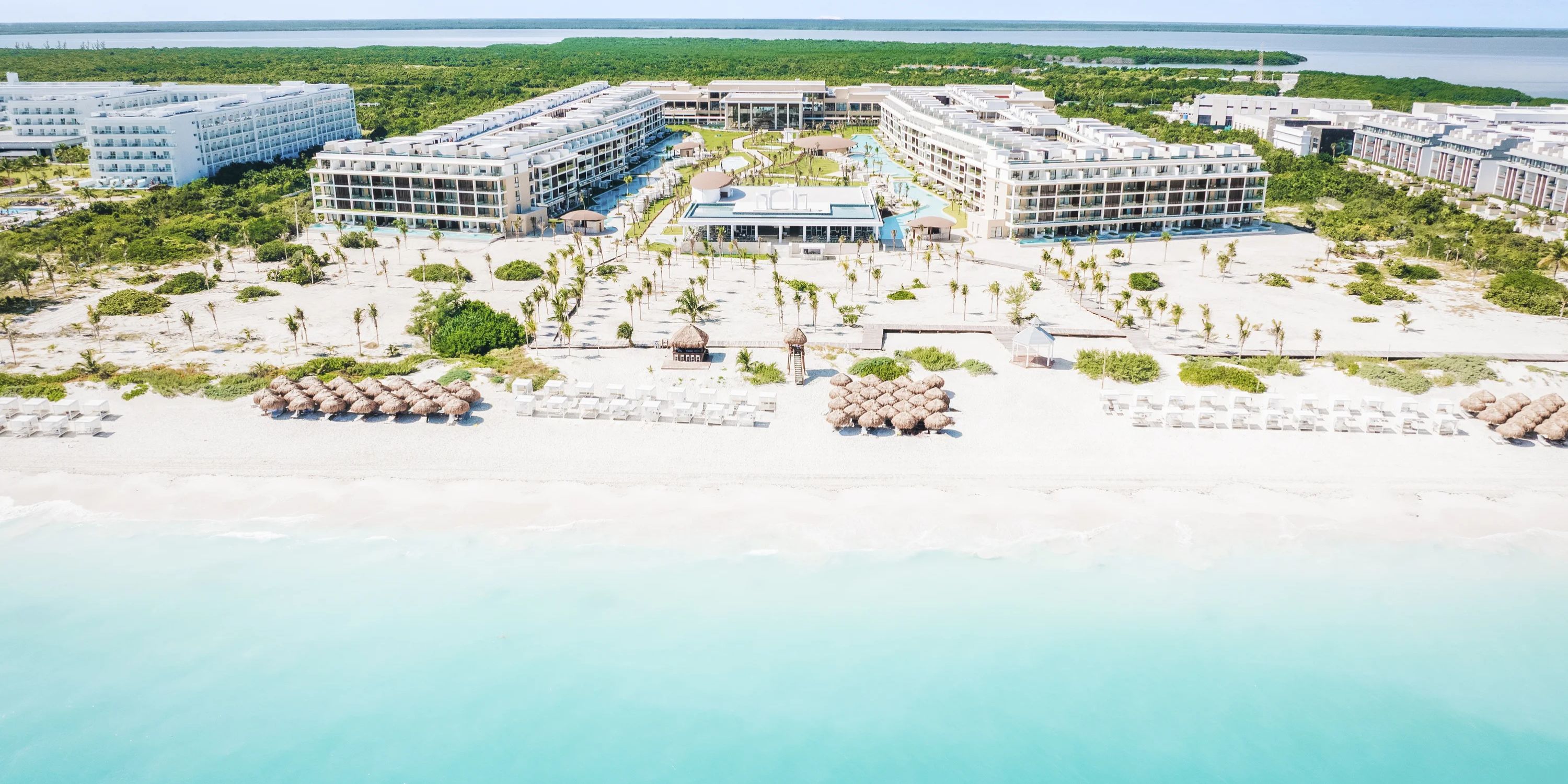 Aerial view of a destination wedding at Majestic Mirage Costa Mujeres with umbrellas, pools, and greenery.
