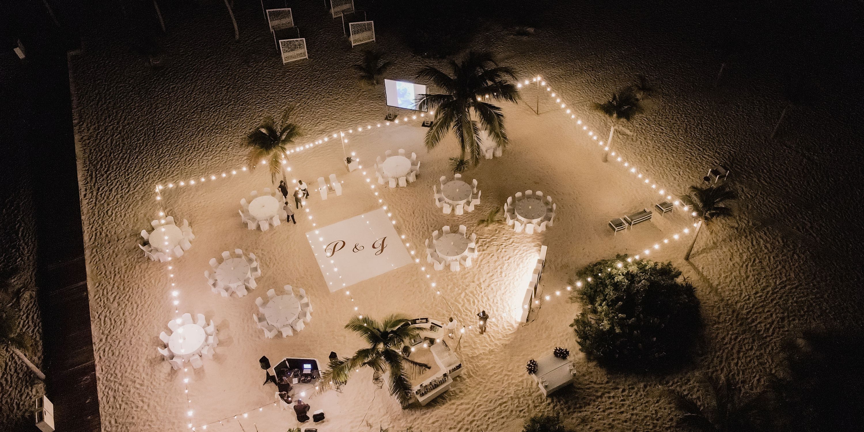 Aerial view of a destination wedding at Majestic Mirage Costa Mujeres with round tables and glowing lights.