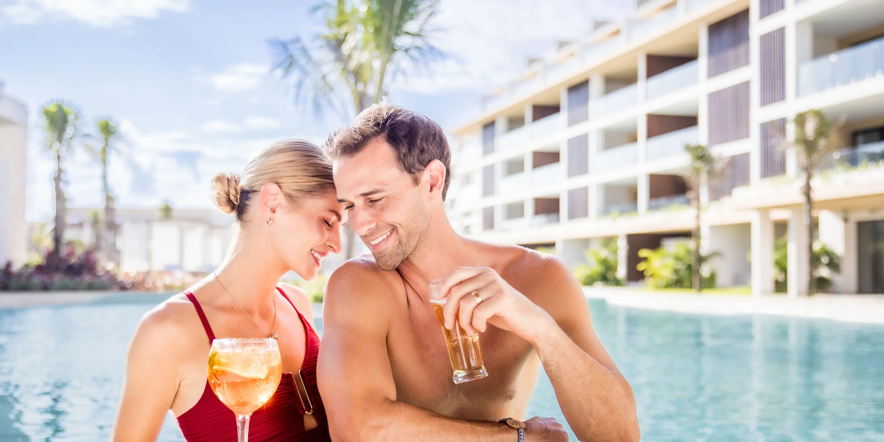 A couple enjoys drinks by the pool at Majestic Mirage Costa Mujeres during their destination wedding.