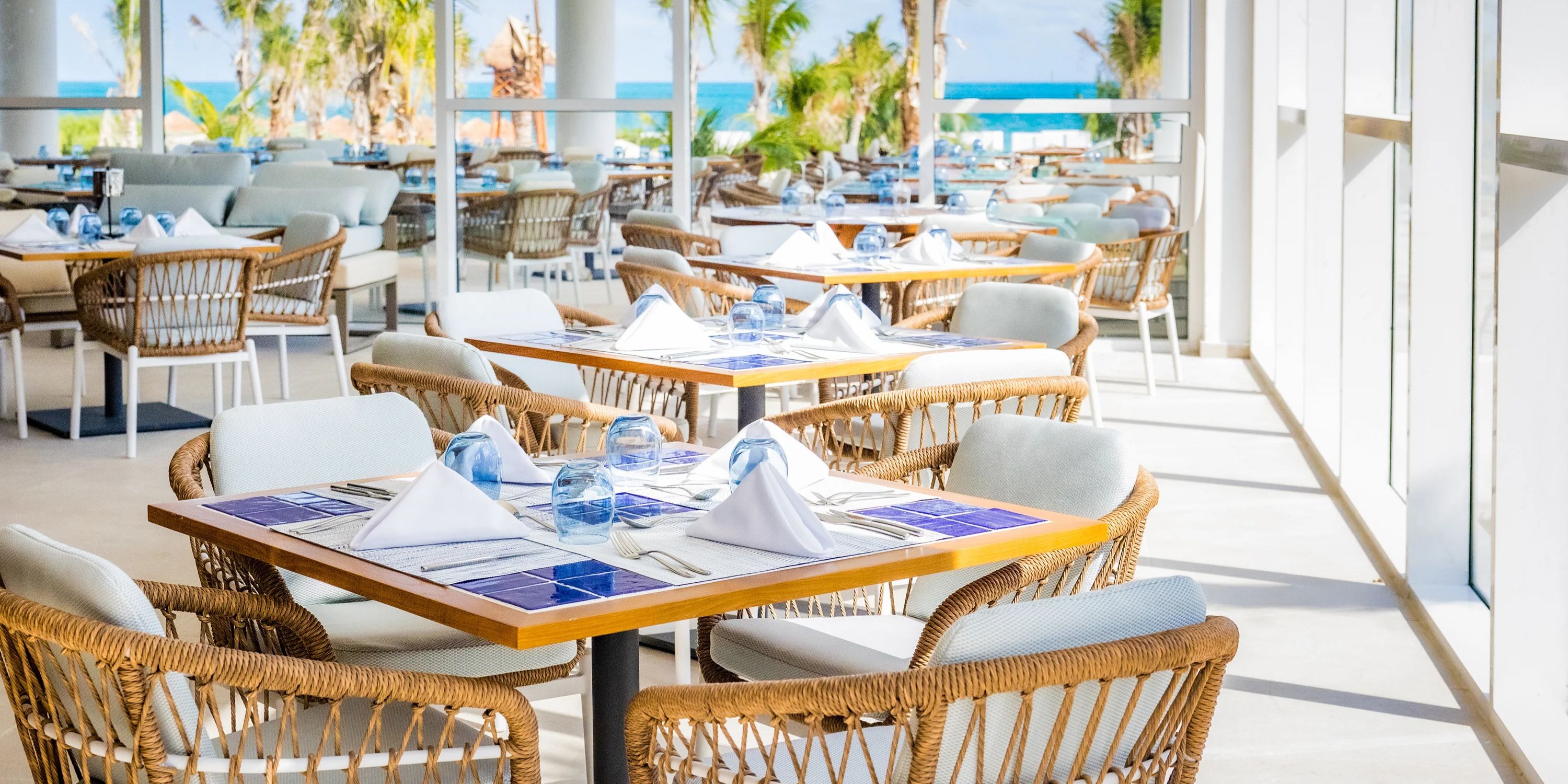 Outdoor restaurant with set tables and wicker chairs, perfect for a destination wedding at Majestic Mirage.
