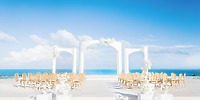 Destination wedding at Majestic Mirage Costa Mujeres with white arches, chairs, and stunning ocean view.