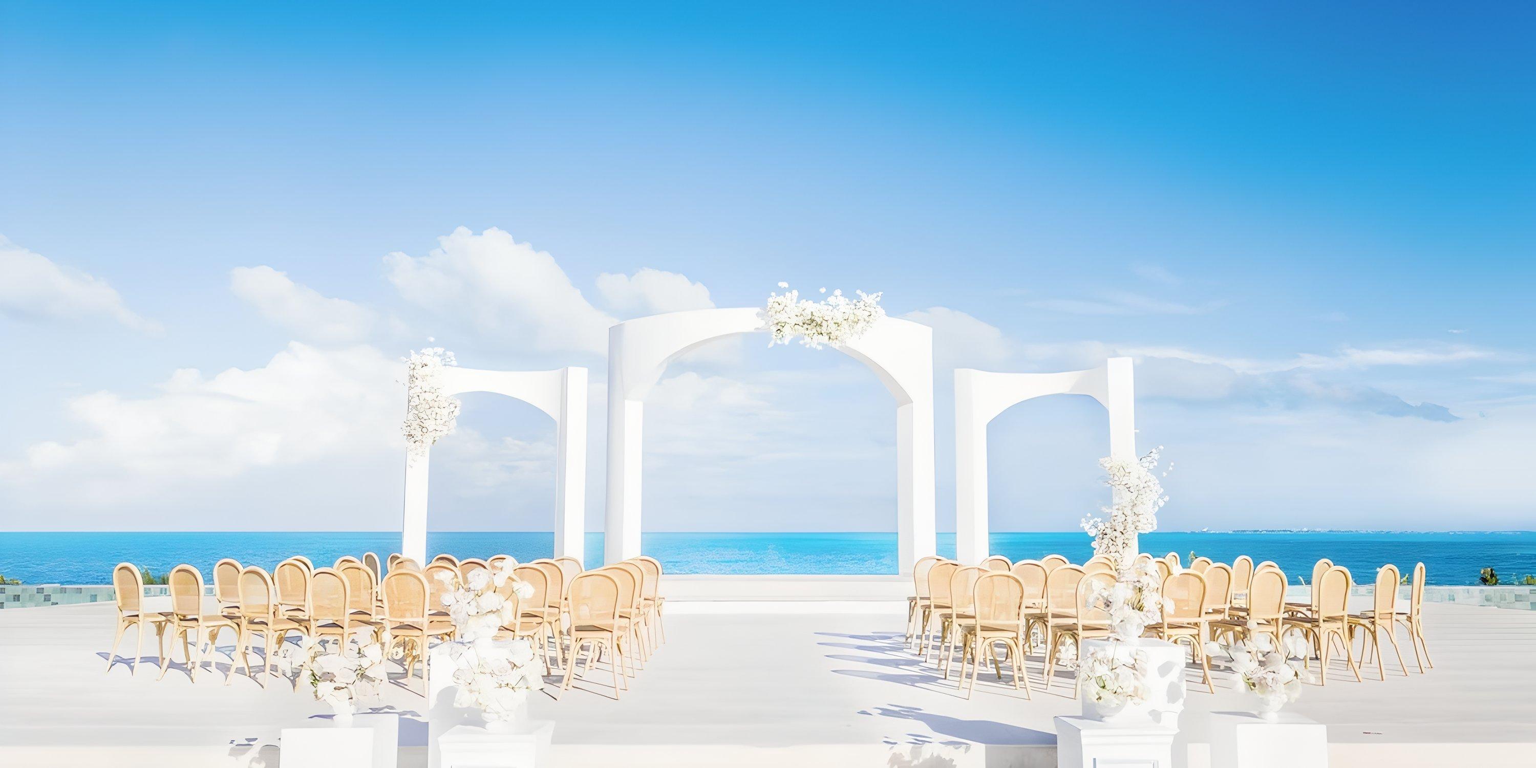 Destination wedding at Majestic Mirage Costa Mujeres with white arches, chairs, and stunning ocean view.