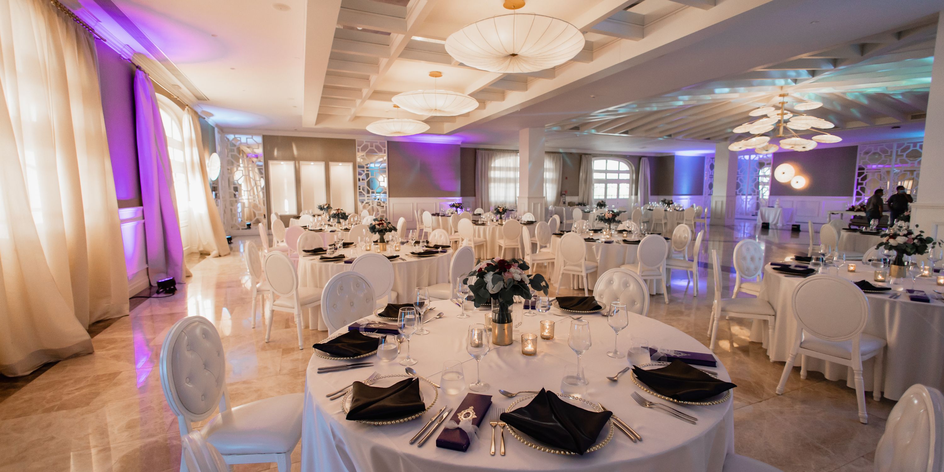 Luxurious banquet hall for destination weddings at Majestic Mirage Costa Mujeres, round tables, purple lighting.