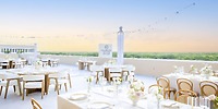 Rooftop wedding venue with white tables, floral centerpieces, and sunset views at Majestic Mirage Costa Mujeres.