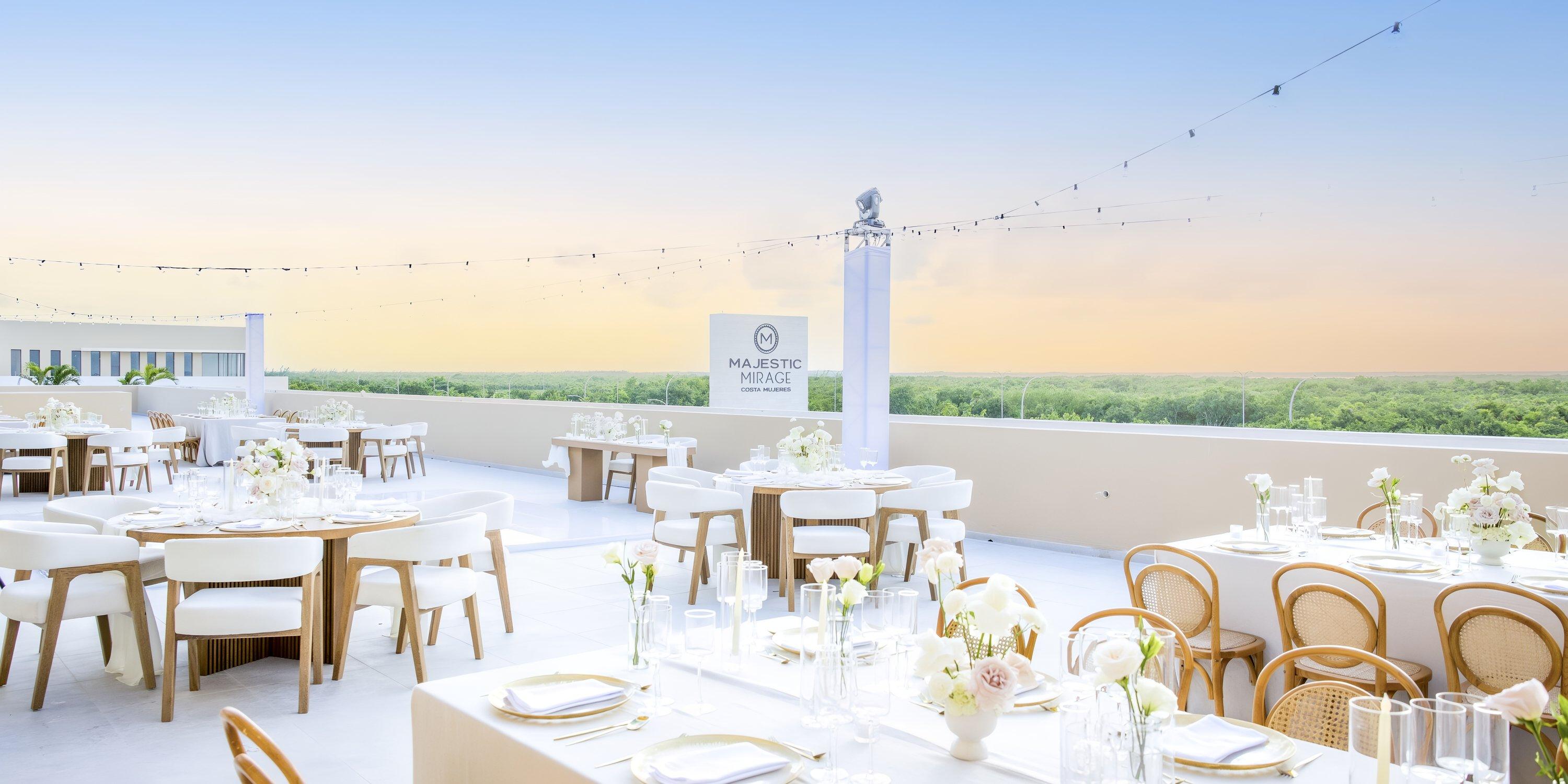Rooftop wedding venue with white tables, floral centerpieces, and sunset views at Majestic Mirage Costa Mujeres.