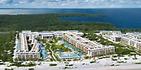 A breathtaking aerial view of Majestic Mirage Costa Mujeres resort, an idyllic destination wedding venue surrounded by lush greenery and shimmering water.