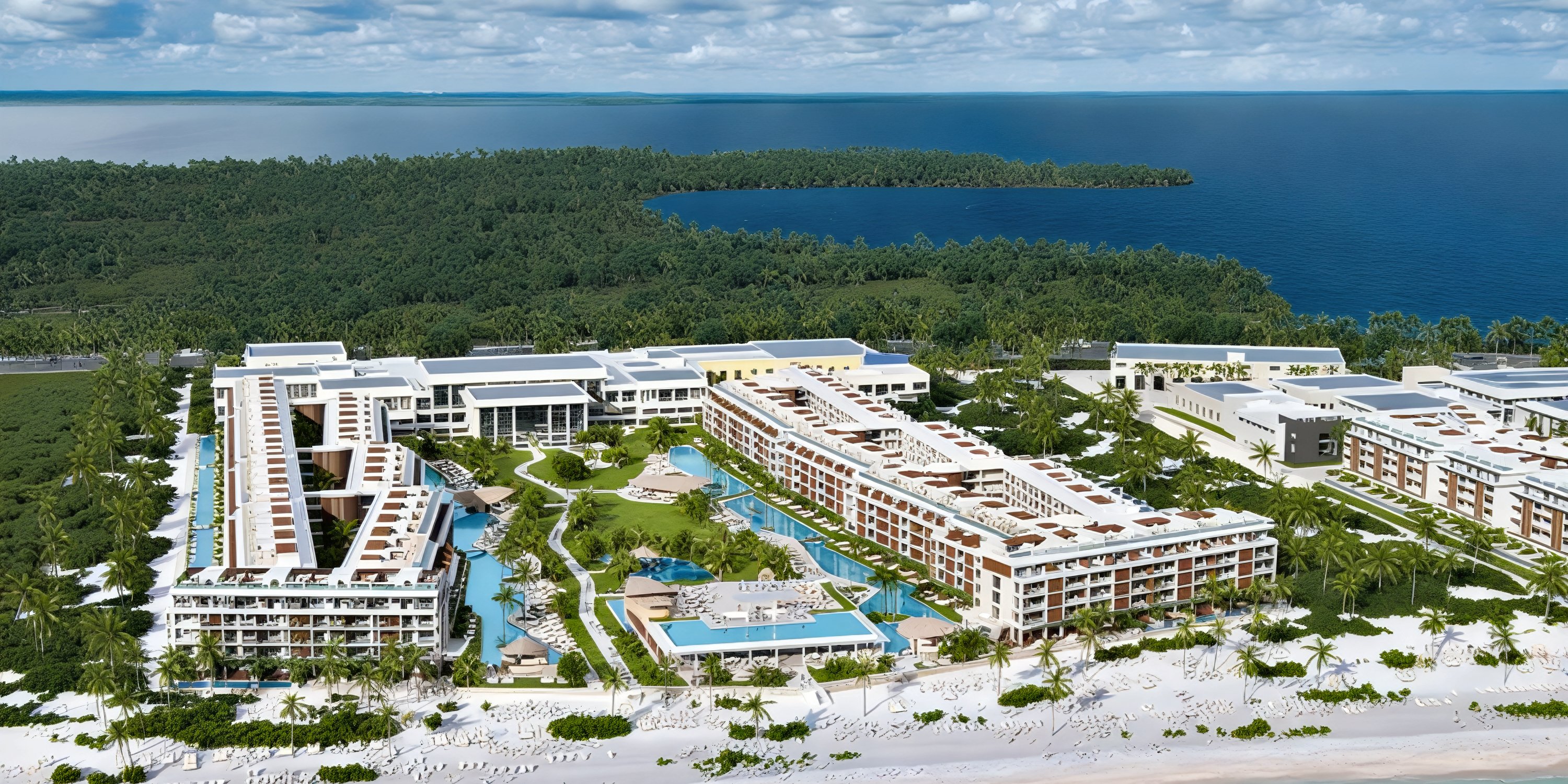 A breathtaking aerial view of Majestic Mirage Costa Mujeres resort, an idyllic destination wedding venue surrounded by lush greenery and shimmering water.