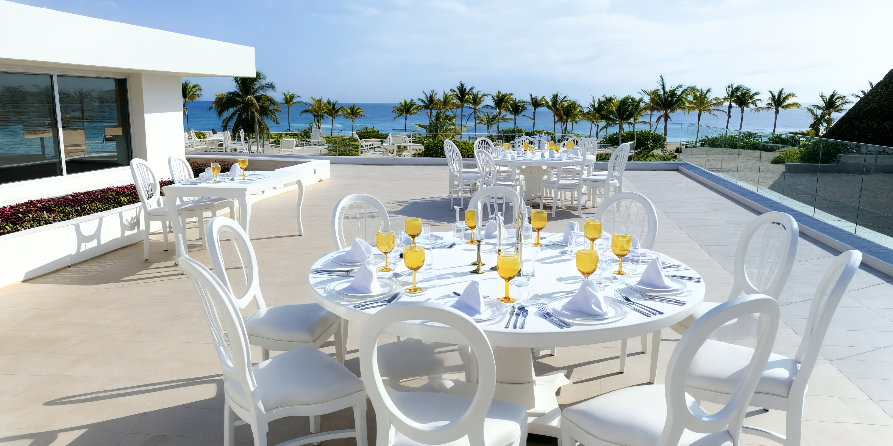 White tables adorned with orange drinks set the scene for a stunning destination wedding on the terrace at Majestic Mirage Costa Mujeres.