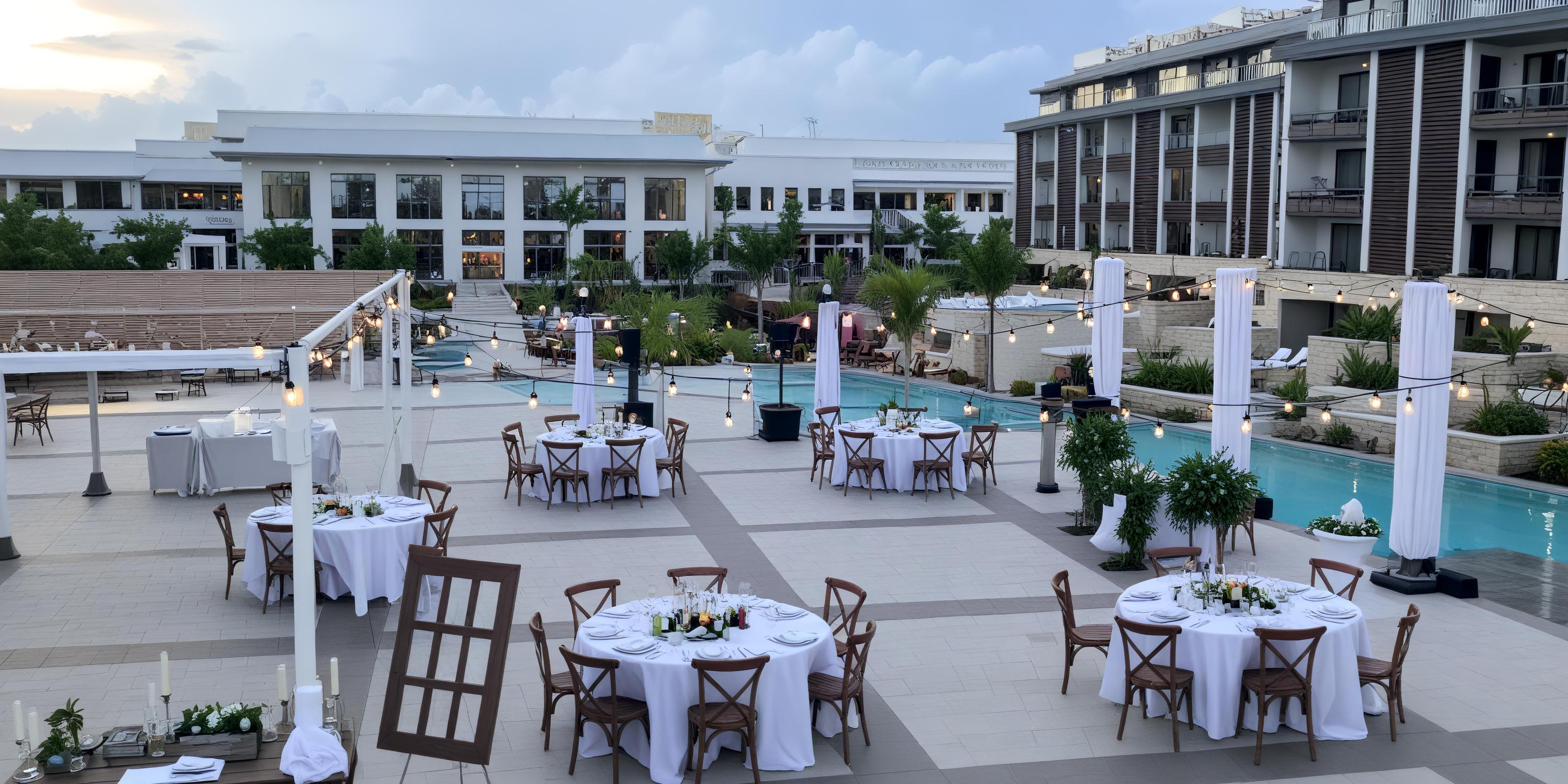 Elegant outdoor poolside destination wedding reception at Majestic Mirage Costa Mujeres, featuring round tables adorned with white linens.