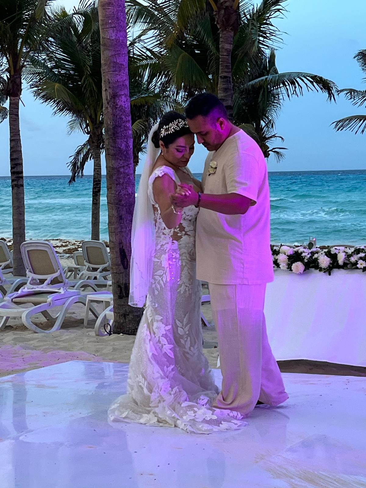 Camille and Jeff share a dance at their destination wedding, surrounded by palm trees and stunning ocean views at a beautiful beachside venue.