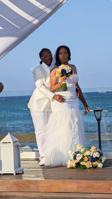 Grace and Mohammed (Copy): Two women in wedding gowns stand by the ocean, holding a bouquet, celebrating their destination wedding.