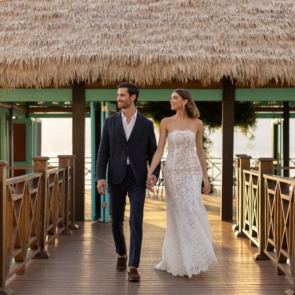 A couple dressed in formal attire walks hand in hand, capturing the essence of 2025's destination wedding trends.