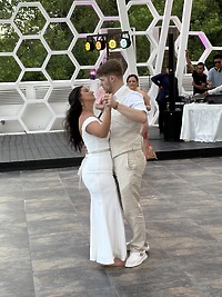Aubrey and Noah dance in white attire on a tiled floor at an outdoor destination wedding.