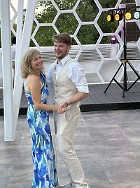Aubrey and Noah share a formal dance outdoors by a honeycomb-patterned wall, celebrating their destination wedding.