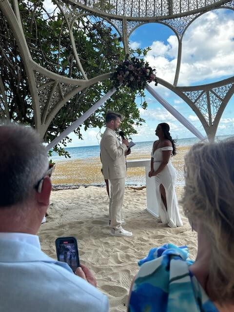 Aubrey and Noah exchanged their wedding vows on a sandy beach beneath a beautiful canopy, while guests looked on during their stunning destination wedding.
