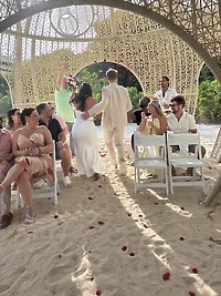 Aubrey and Noah: A beautiful destination wedding on a sandy beach, with seated guests and rose petals scattered along the aisle.