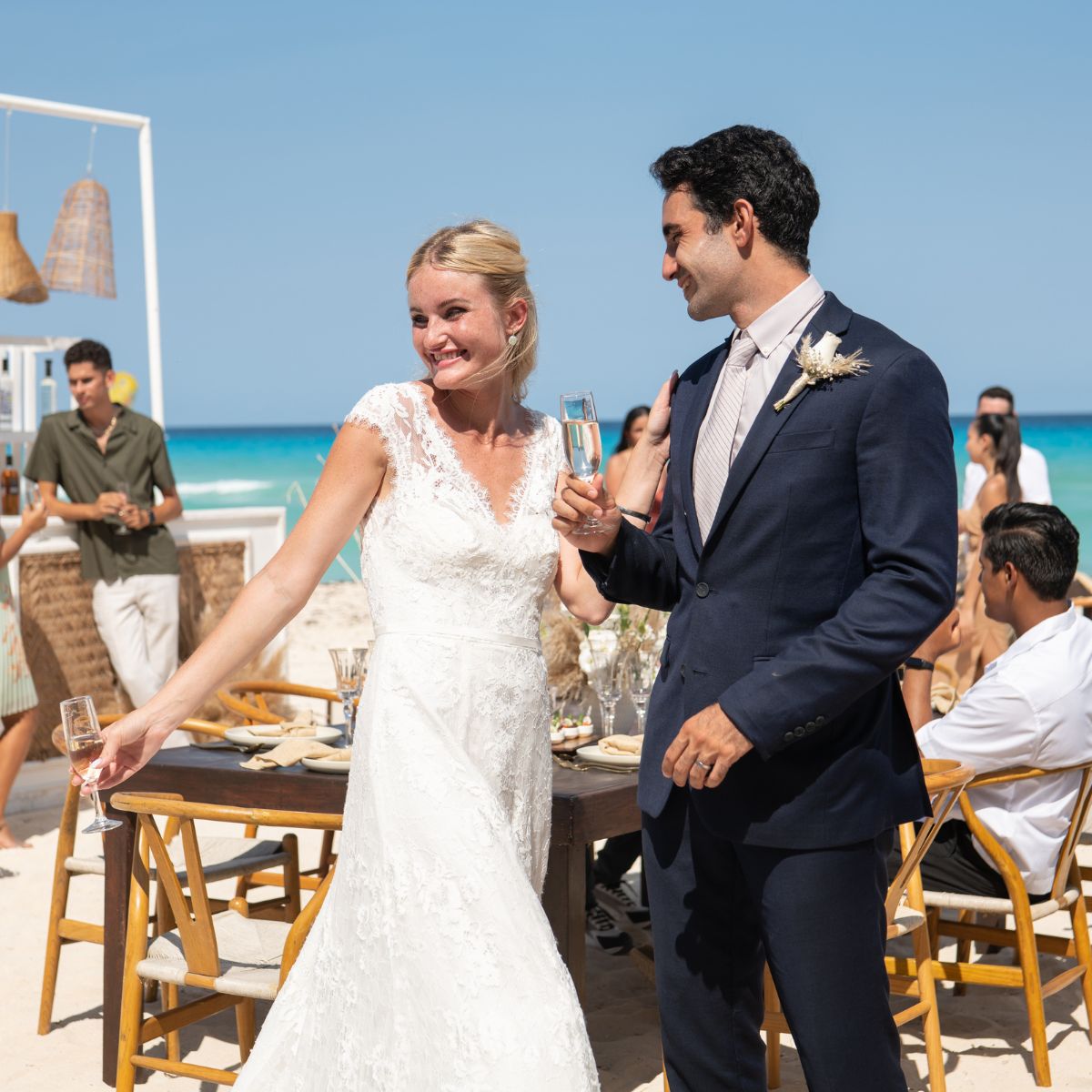 The bride and groom share a champagne toast during their intimate destination wedding reception on the beach.
