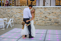 Camille and Jeff share a joyful dance with a young girl in white dresses on the illuminated floor at their destination wedding.