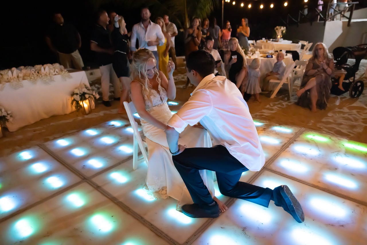 Camille and Jeff share a heartfelt moment on the illuminated dance floor at their destination wedding, as the groom kneels before his bride.