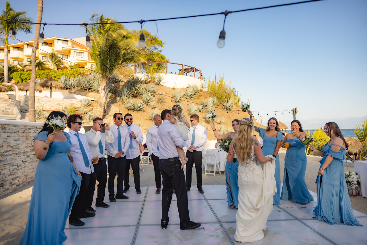Camille and Jeff’s destination wedding celebration features their guests dancing outdoors in elegant blue attire beneath twinkling string lights.