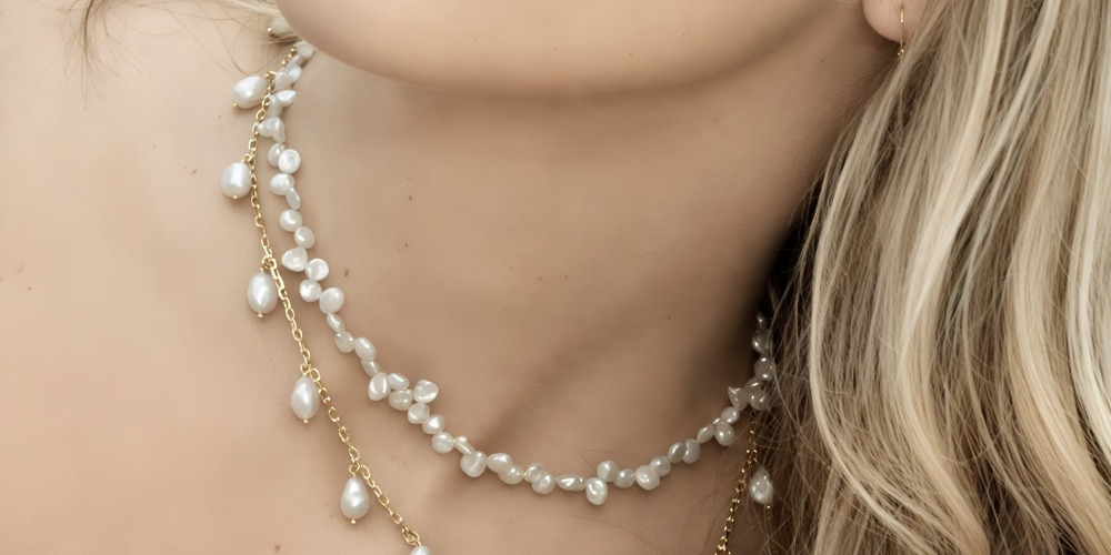 Close-up of a woman attending a destination wedding, showcasing layered pearl and gold chain necklaces, with her blonde hair elegantly framing the jewelry.