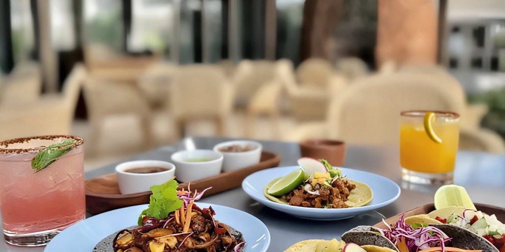 Plates of tacos and drinks are beautifully arranged on a table in a stylish, outdoor restaurant setting, perfect for a vibrant destination wedding celebration.