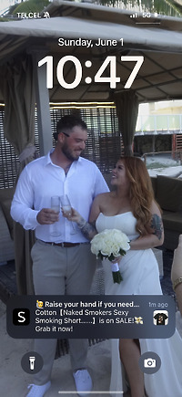 Alexis and Colton stand outdoors at their destination wedding, smiling together as they hold drinks and a bouquet.