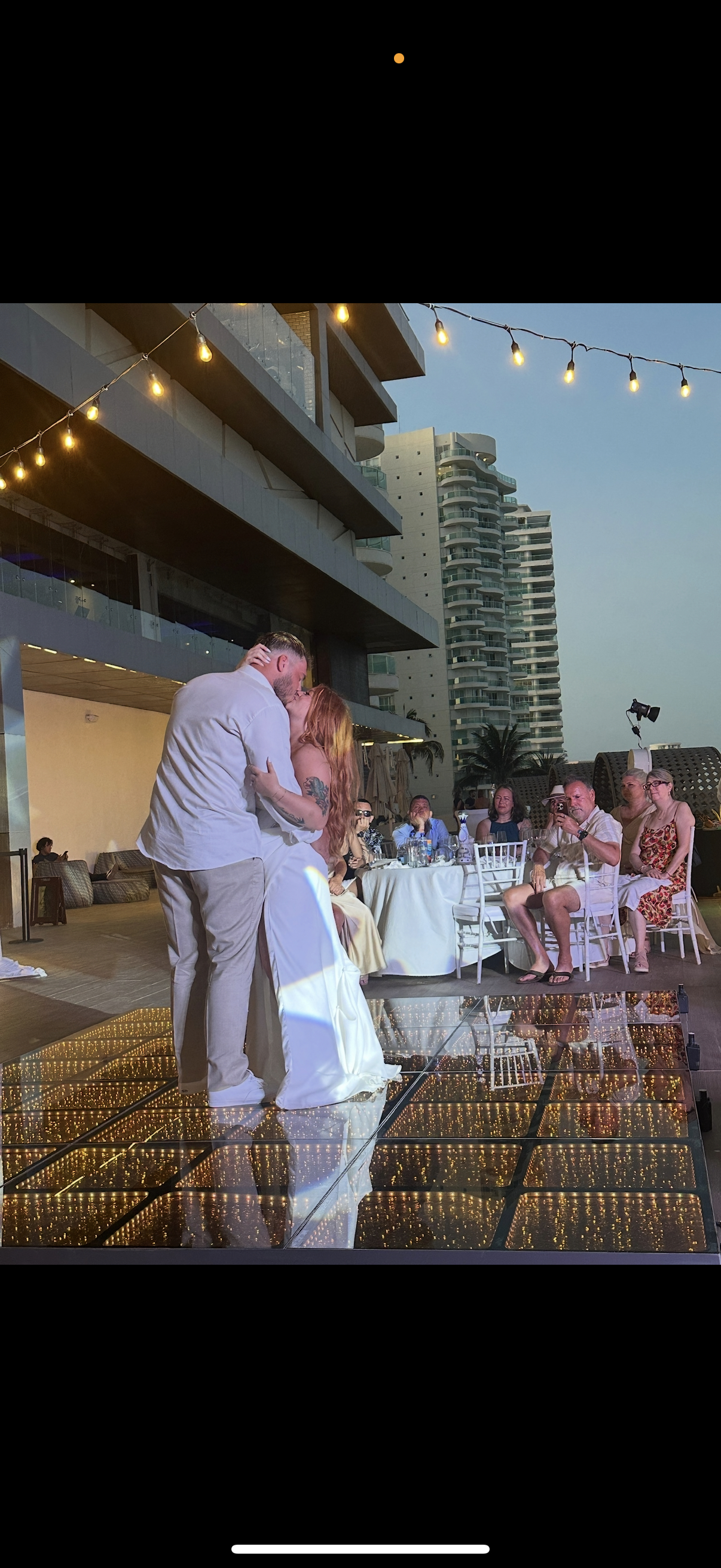 Alexis and Colton share a kiss on the glass dance floor at their outdoor city destination wedding.