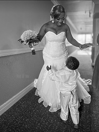 Cynthia and Ruben: At their destination wedding, the bride beams in her wedding dress as she warmly greets a young boy in the hallway.