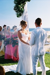 Alexis and Colton stand facing each other during their destination wedding ceremony on the beach.