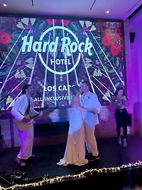 Alexis and Colton share a dance on stage at the Hard Rock Hotel during their destination wedding, while a live band plays in the background.