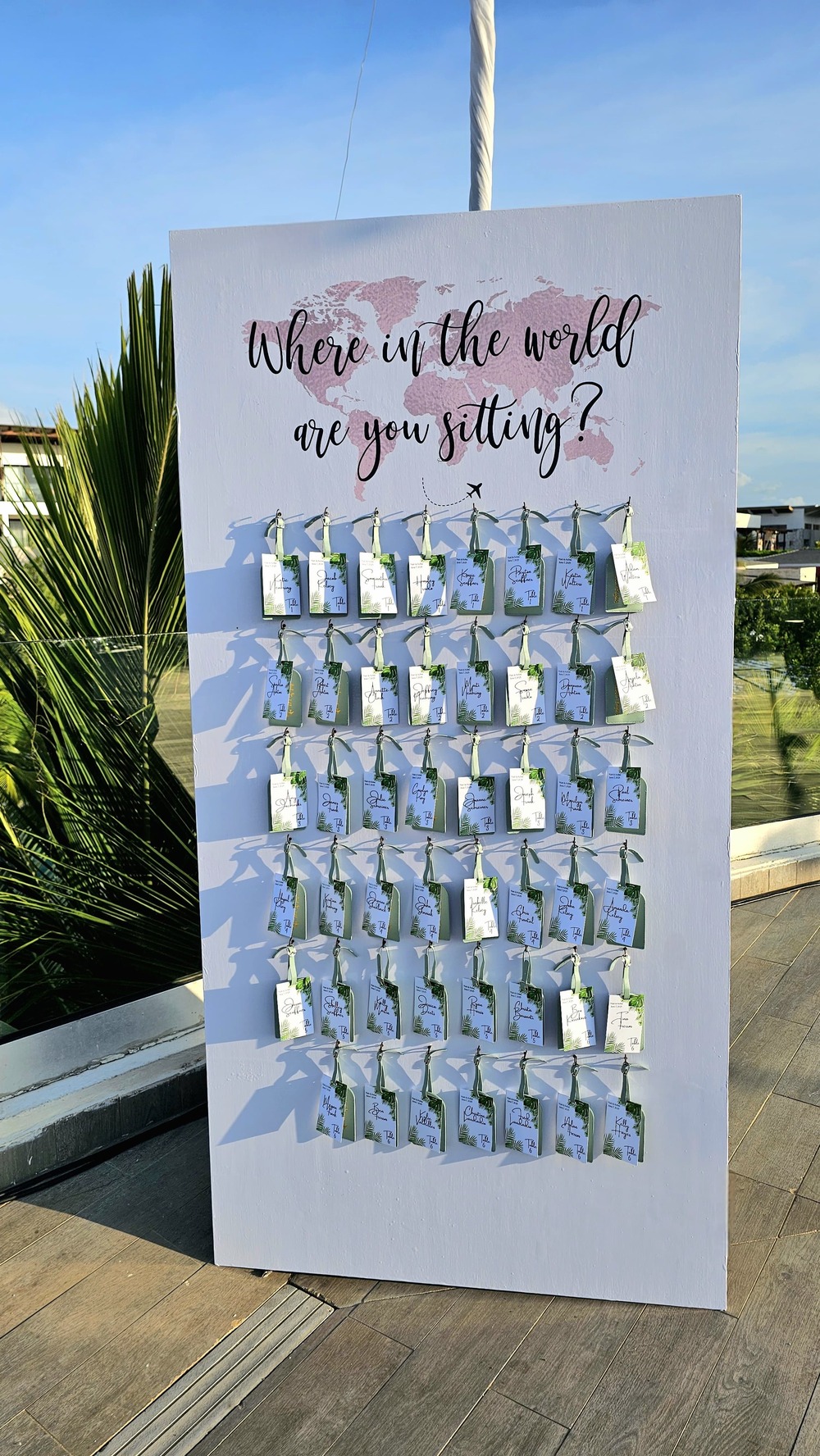 A seating chart board for "Tiana and Steven's Wedding" features cards and the phrase: "Where in the world are you sitting? Find your place and join us on our destination wedding adventure!.