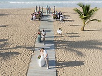 Tiana and Steven share a romantic kiss on a wooden walkway during their beautiful destination wedding by the beach.