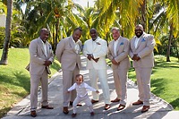 Khadijah and Oscar pose together on a sunny, palm-lined path at their destination wedding.