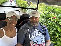 Jamie and Gary, both sporting matching hats, enjoy a ride together through lush greenery on their destination wedding day.
