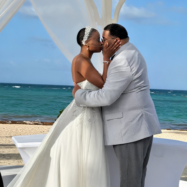 Jamie and Gary share a kiss beneath a white canopy during their beautiful destination wedding by the beach.