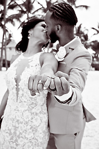 Trey and Kimberly share a kiss on the beach, proudly displaying their wedding rings to the camera during their destination wedding.