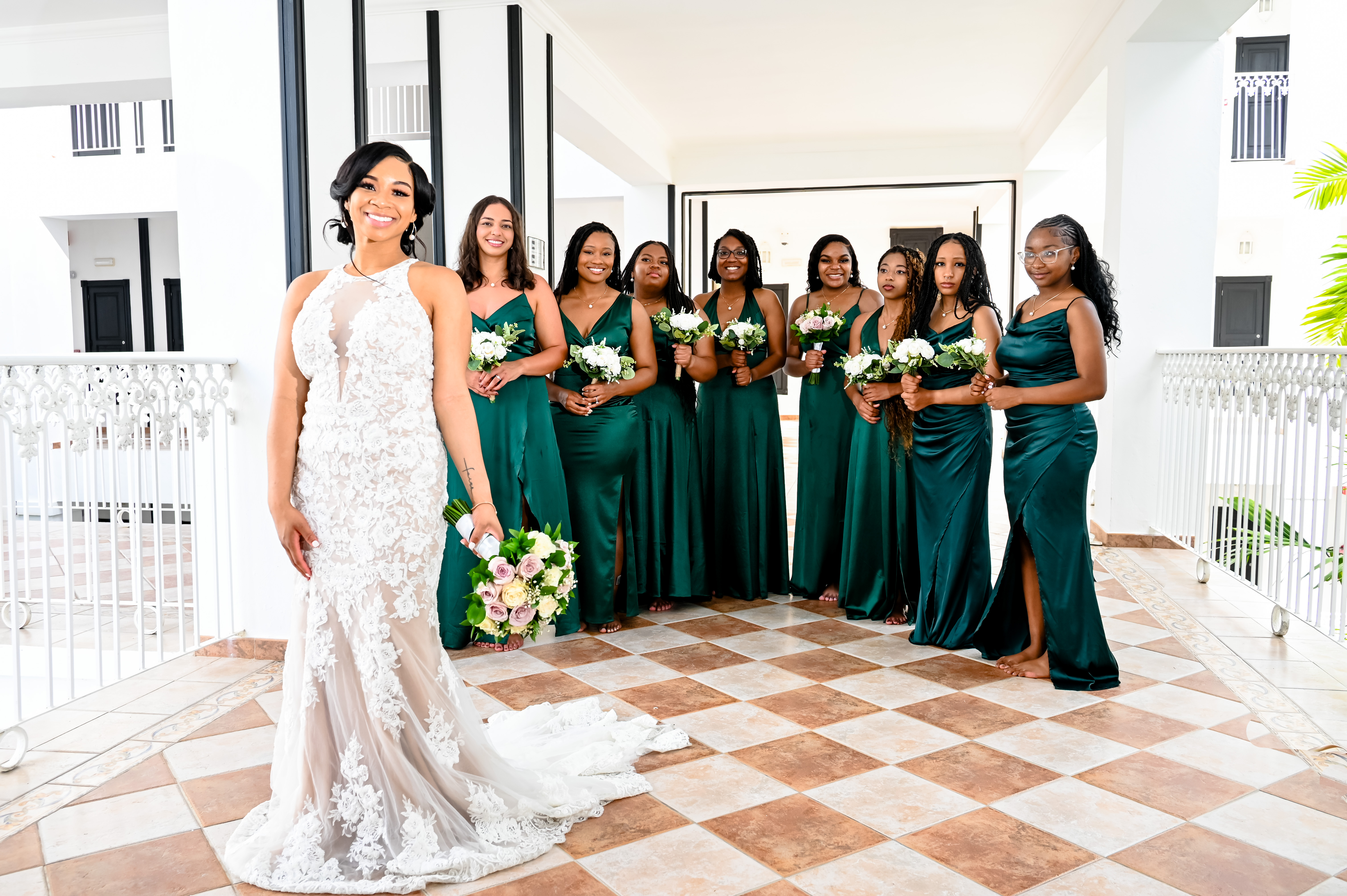 At a destination wedding, the bride in white stands with her bridesmaids dressed in green, all holding bouquets—Trey and Kimberly.