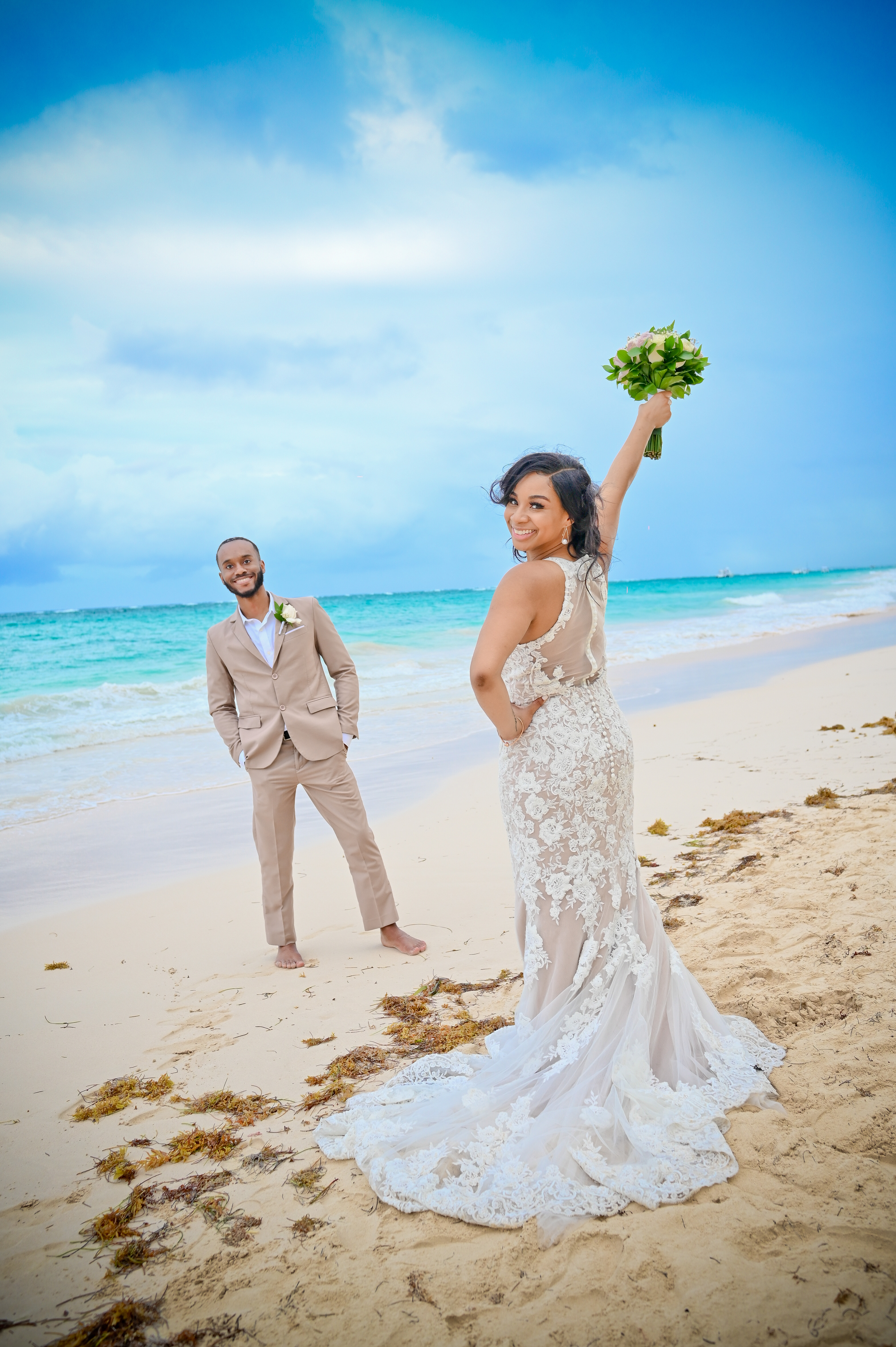 Trey and Kimberly (Copy): Bride holding a bouquet on the beach during their destination wedding, with the groom in formal attire standing behind her.