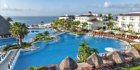 Moon Palace Nizuc offers a spacious pool surrounded by loungers and palm trees with stunning ocean views—an idyllic setting for a wedding or destination wedding celebration.