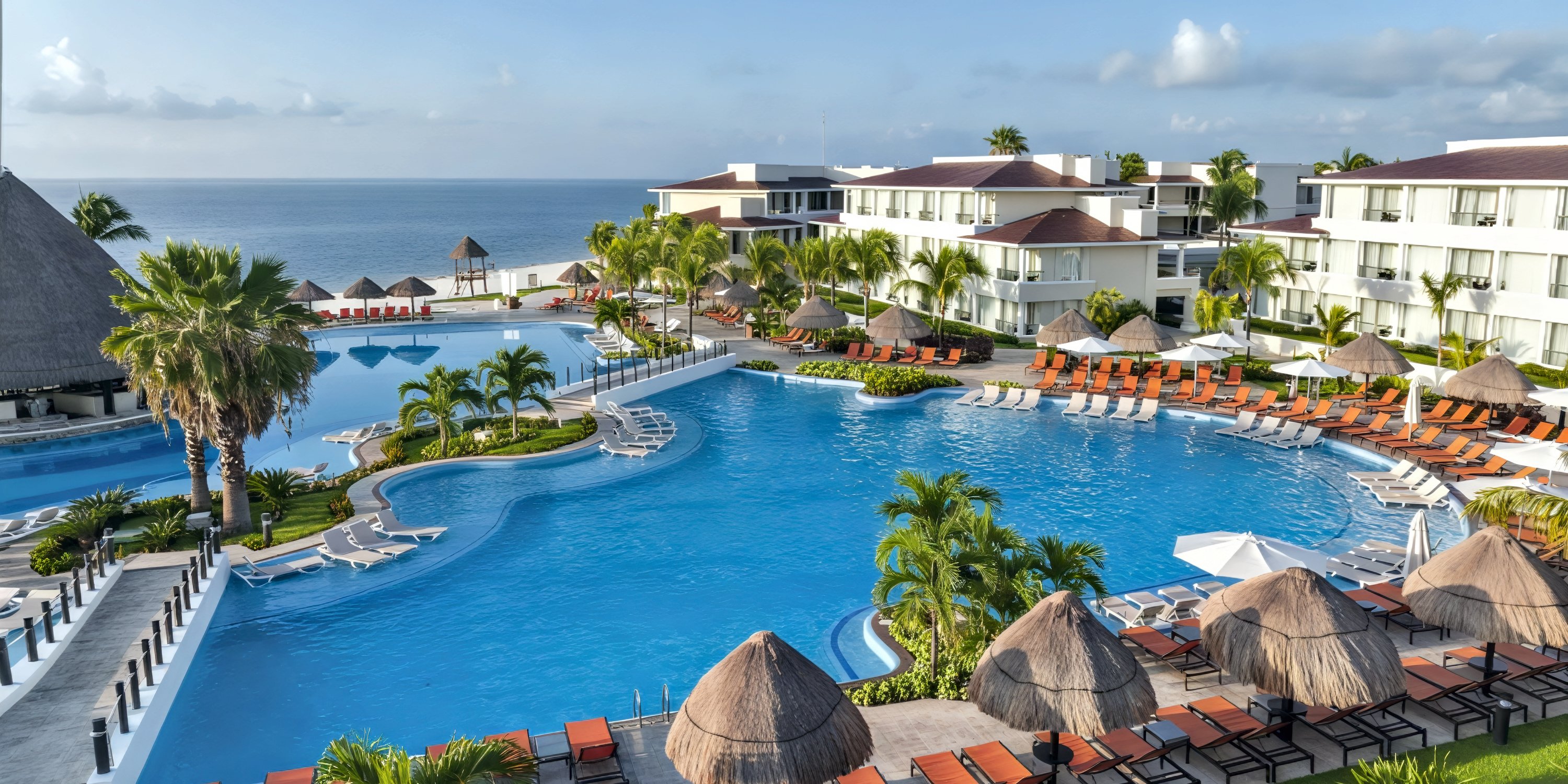 Moon Palace Nizuc offers a spacious pool surrounded by loungers and palm trees with stunning ocean views—an idyllic setting for a wedding or destination wedding celebration.