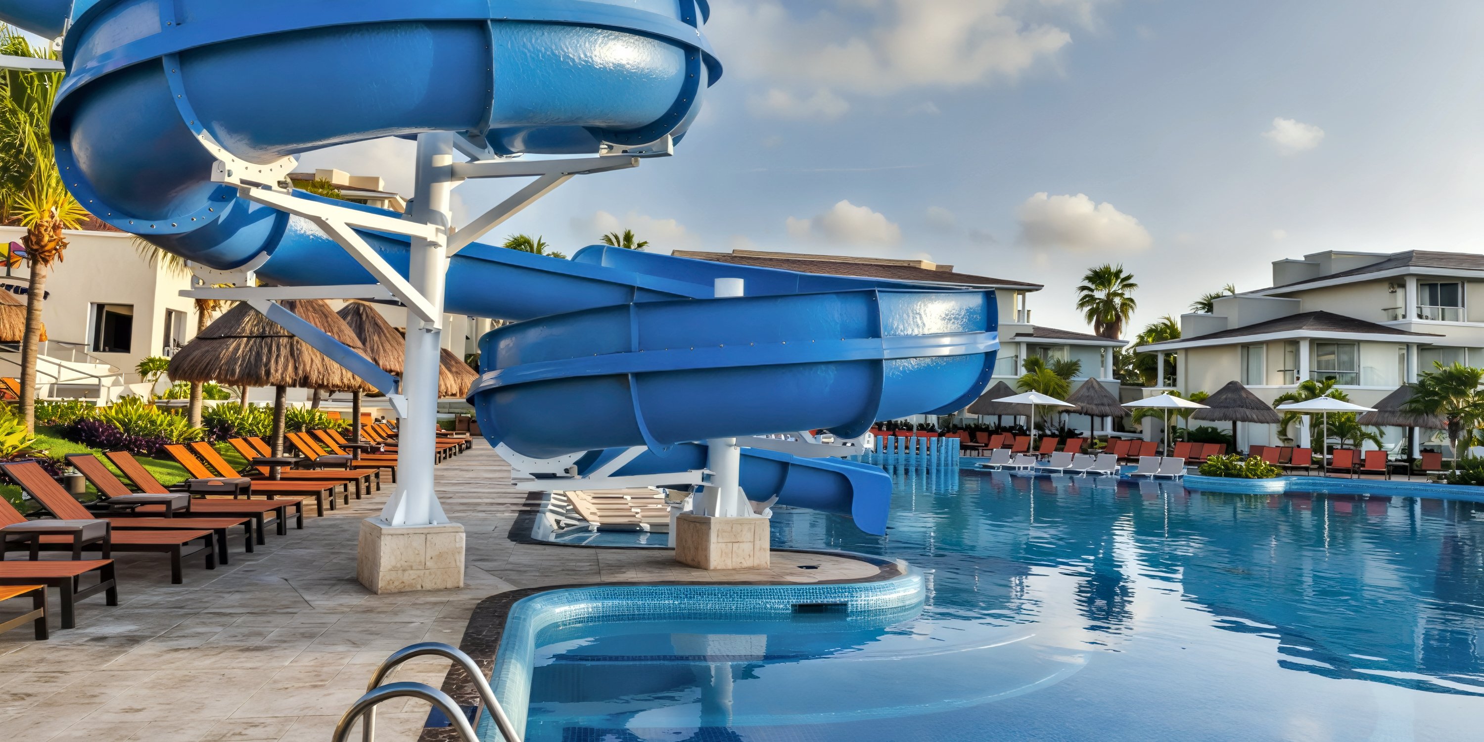 A large blue waterslide by the Moon Palace Nizuc resort pool, surrounded by lounge chairs and umbrellas—an ideal spot for relaxation during a destination wedding.