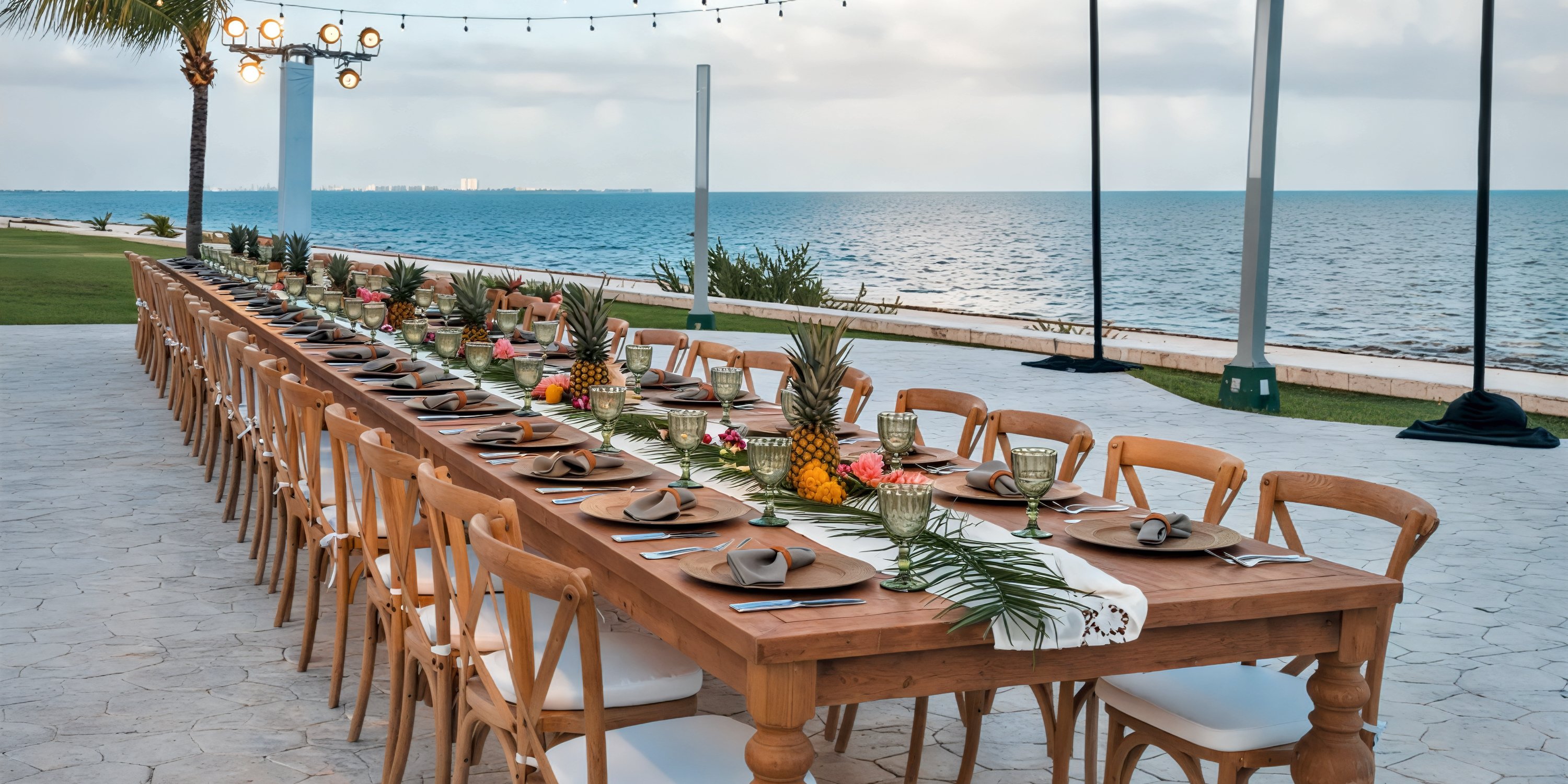 An elegantly decorated outdoor dining table set for a destination wedding at Moon Palace Nizuc, featuring pineapples as centerpieces and overlooking the ocean.