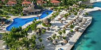 Aerial view of Ocean Coral and Turquesa resort, featuring a stunning pool, swaying palm trees, and inviting lounge chairs by the ocean—an idyllic setting for a destination wedding.