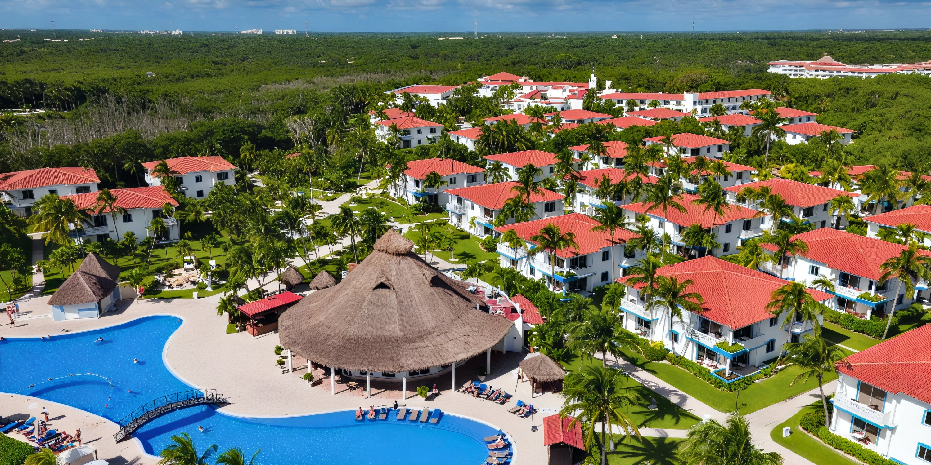 Aerial view of Ocean Coral and Turquesa, a stunning destination wedding resort featuring red-roofed buildings, swaying palm trees, and a sprawling pool.