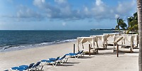 Lounge chairs and cabanas line the beach at Ocean Coral and Turquesa, creating a picturesque setting for a destination wedding under a partly cloudy sky.