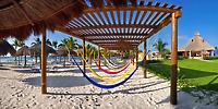 Hammocks sway beneath a pergola on the sandy beach at Ocean Coral and Turquesa, creating the perfect relaxing spot for a destination wedding.