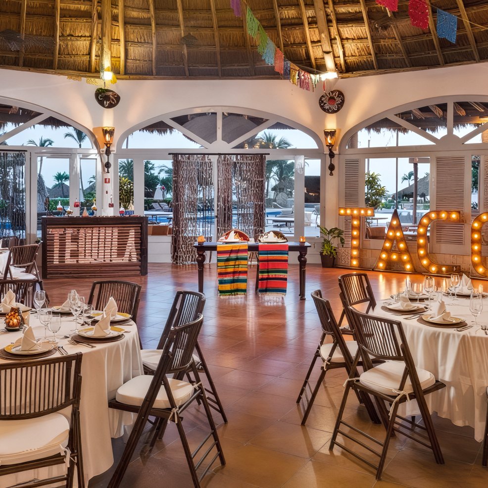 Beautifully decorated indoor wedding venue featuring elegant dining tables, a vibrant taco station, and festive lighting—perfect for a memorable destination wedding celebration.